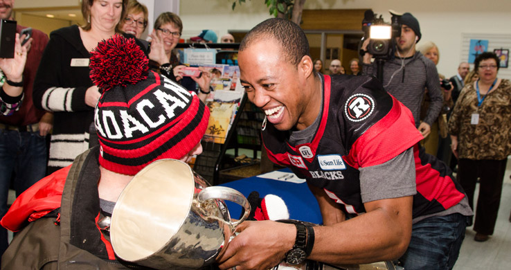 Henry Burris holding the Grey Cup with a client at The Royal