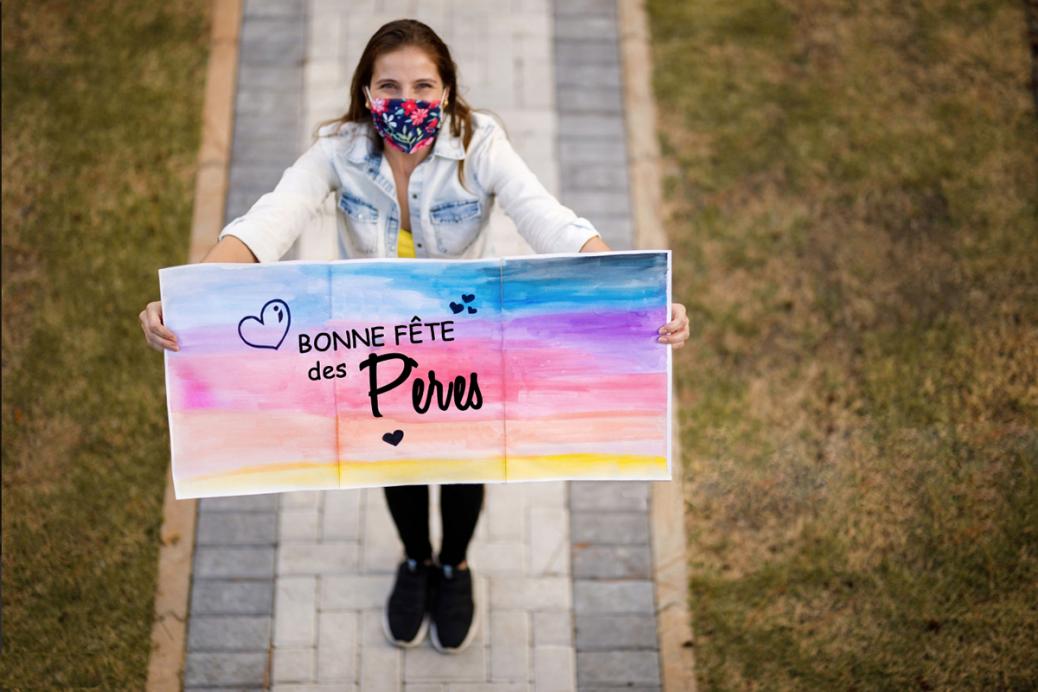 Une femme avec un enseigne souhaitant une Bonne fête des pères