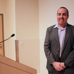 Dr. Tyler Black standing behind podium giving his presentation