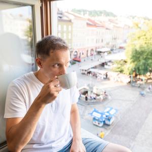 Un homme avec un café près d'une fenêtre ouverte