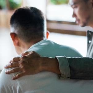 Un homme qui console un autre homme avec une main sur l'épaule