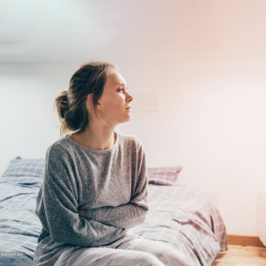 Woman sitting on the side of a bed.