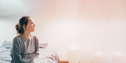 Woman sitting on the side of a bed.